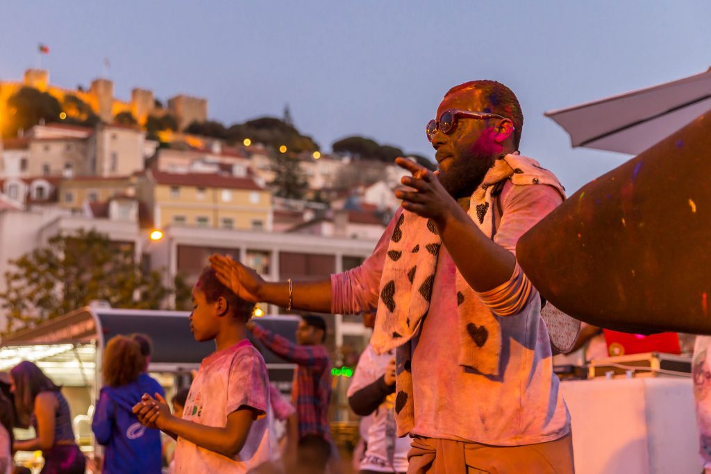 man dancing during the holi festival with Martim Moniz property in the background.