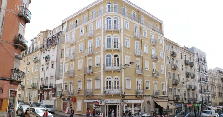 Prédio em tons de amarelo claro, com 4 pisos, numa rua do centro de Lisboa, Portugal