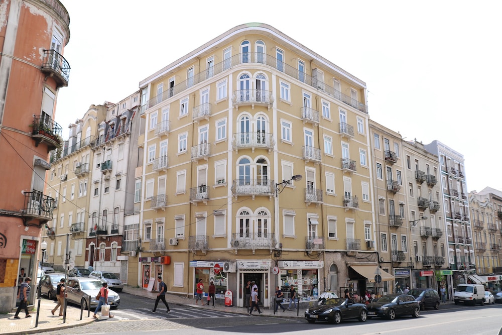 Prédio em tons de amarelo claro, com 4 pisos, numa rua do centro de Lisboa, Portugal