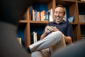 Massimo Forte, influencer del mercato immobiliare, seduto nella sua biblioteca giocando con un cubo di Rubrik