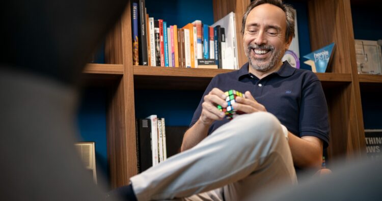 Massimo Forte, influencer del mercato immobiliare, seduto nella sua biblioteca giocando con un cubo di Rubrik