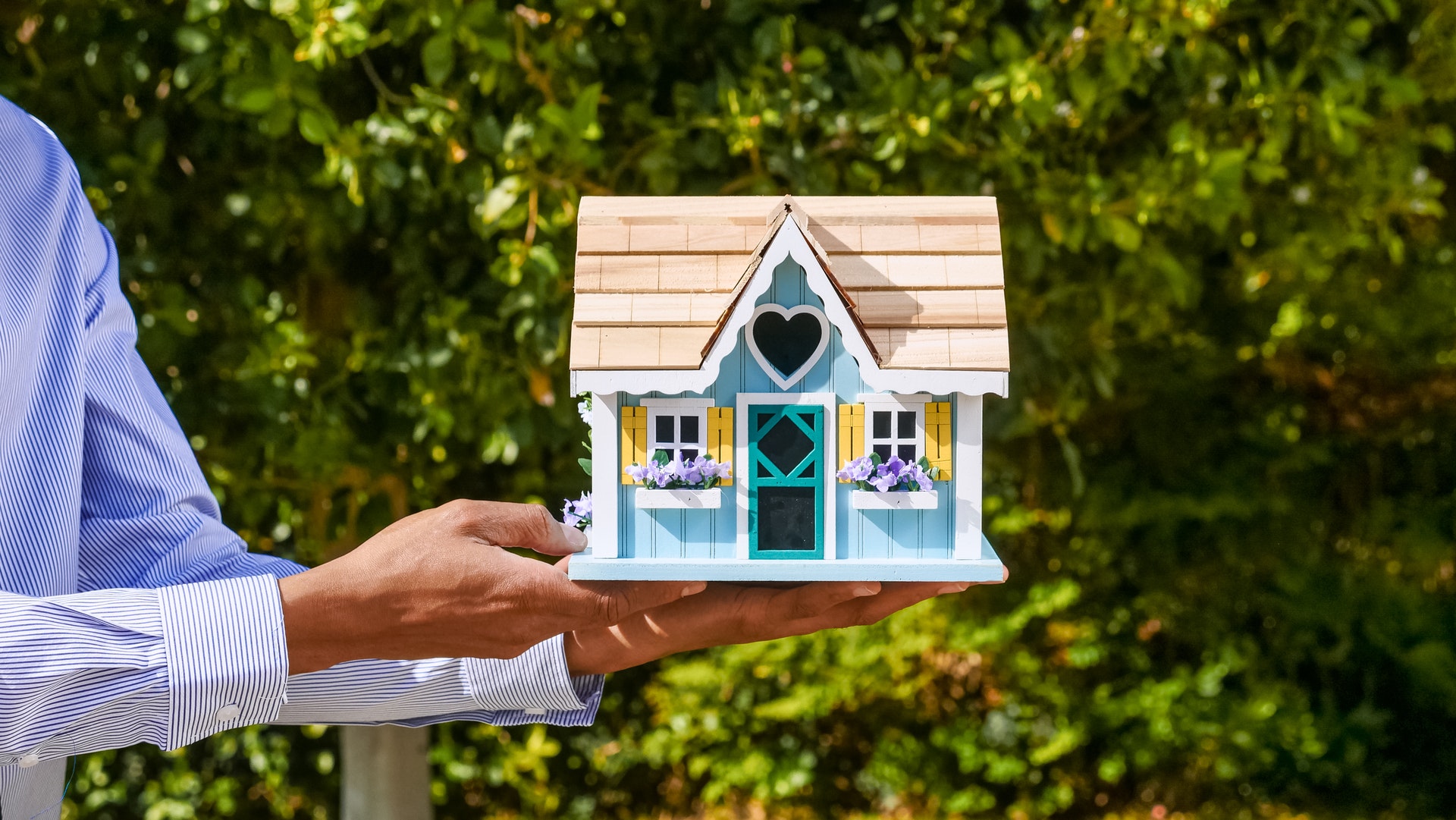 Professionnel de l'immobilier tenant une maison de poupée, symbolisant à quel point il est facile d'acheter et de vendre des maisons avec des iBuyers